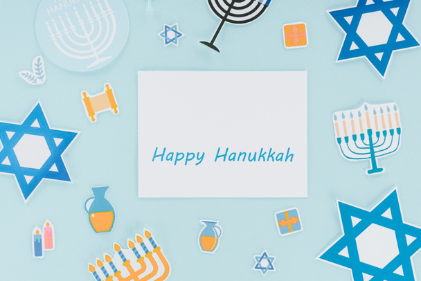 piso con carteles de papel de vacaciones hannukah y feliz tarjeta hannukah aislado en azul, concepto hannukah
 - Foto, Imagen