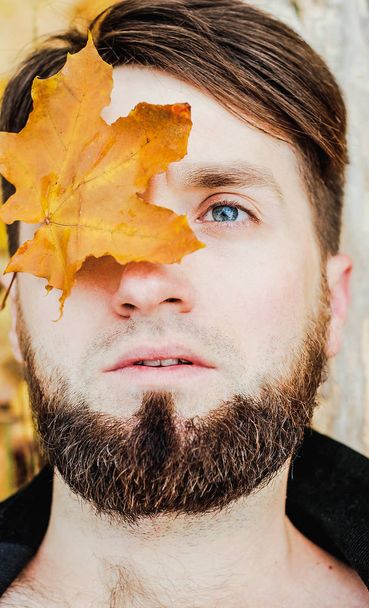 Moda de outono sazonal. Retrato de um homem cobrindo seu rosto com uma folha de outono
. - Foto, Imagem
