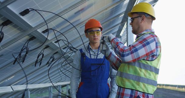 Men learning how to plug in solar panels - Фото, зображення