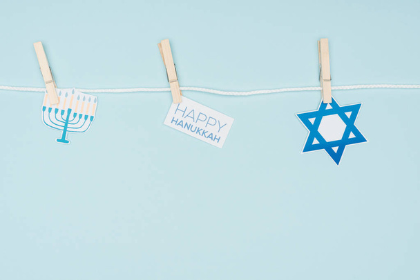 vista superior de carteles de papel de vacaciones hannukah fijados en la cuerda aislada en azul, concepto hannukah
 - Foto, Imagen