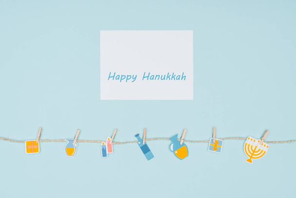 top view of happy hannukah card and holiday paper signs pegged on rope isolated on blue, hannukah concept - Photo, Image