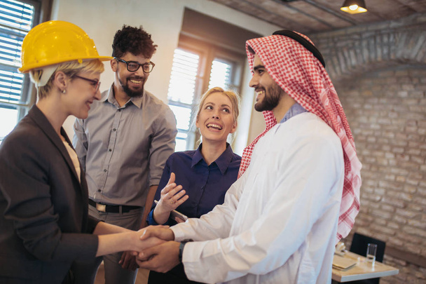 Grupo alegre de equipo de negocios dando la bienvenida a empresario árabe
 - Foto, imagen