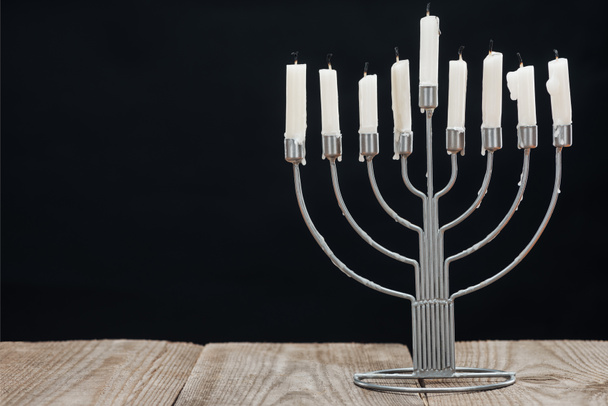 close up view of jewish menorah with candles for hannukah holiday celebration on wooden tabletop isolated on black, hannukah concept - Photo, Image