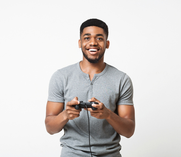 Happy black guy holding joystick and playing video games - 写真・画像