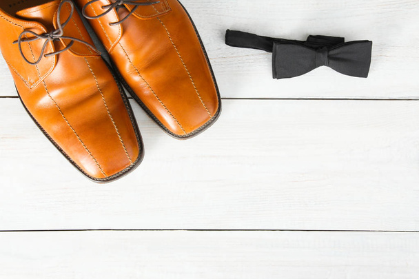 Men's shoes and bow tie on wooden background. Top view, copy space. - Fotó, kép