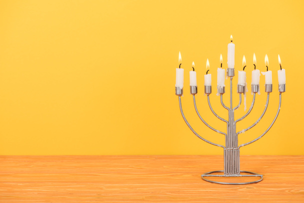 close up view of menorah with candles for hannukah holiday celebration on wooden tabletop isolated on yellow, hannukah concept - Photo, Image
