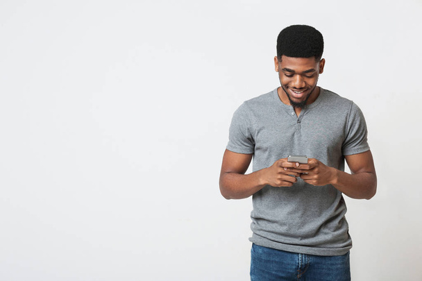 Interesado hombre afroamericano usando teléfono inteligente sobre fondo blanco
 - Foto, Imagen