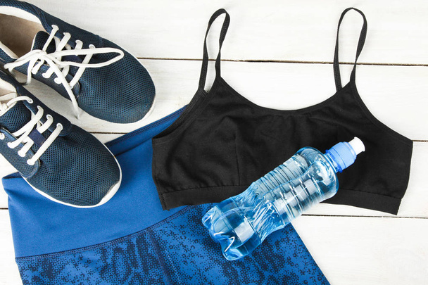 Спортивная одежда и бутылка воды на деревянном фоне. Концептуальный спорт
. - Фото, изображение