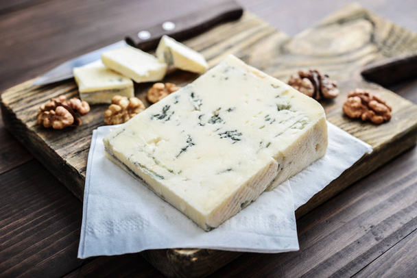 Φέτα τυρί Gorgonzola σε ξύλο κοπής σερβίρεται με closeup σταφυλιών και ξηρούς καρπούς - Φωτογραφία, εικόνα