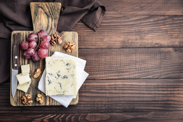 Slice of Gorgonzola cheese on cutting board served with grape and nuts top view - Фото, зображення