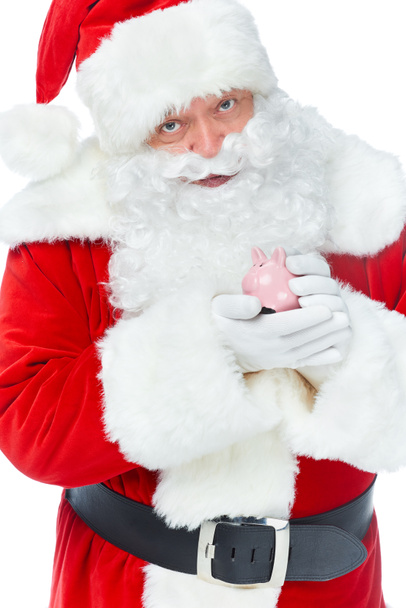 bärtiger Weihnachtsmann hält Sparschwein mit Ersparnissen isoliert auf weiß - Foto, Bild