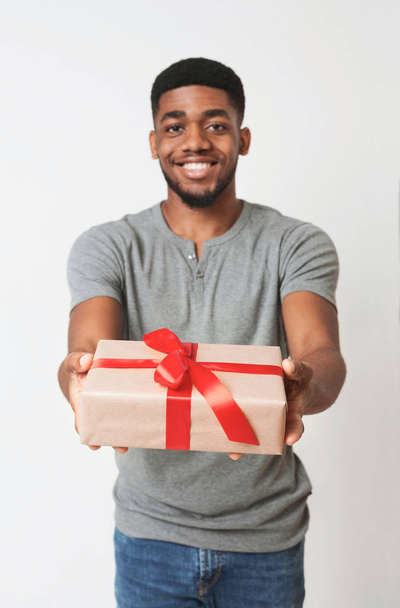 Černý muž v bílém poli držel dárek zabalený s červenou stužkou a luk - Fotografie, Obrázek