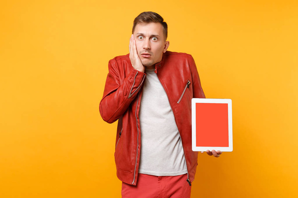 Portré vogue szórakoztató fiatalember a vörös bőr zakó póló hold tabletta pc egészségügyi betét-val üres üres képernyő elszigetelt élénksárga a háttér. Emberek őszinte érzelmek életmód fogalma. Hirdetési területen - Fotó, kép