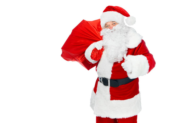 happy santa claus with christmas bag showing thumb up isolated on white - Foto, Imagem