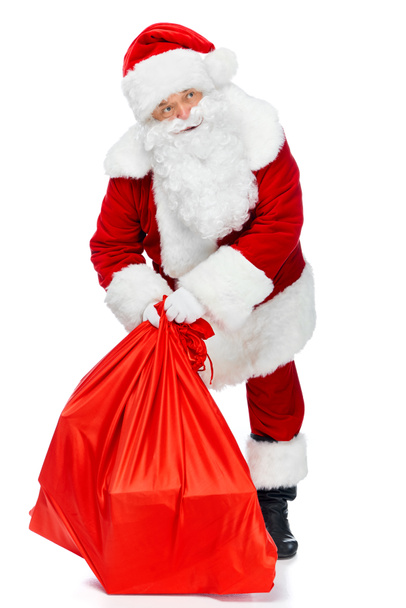 santa claus holding red christmas bag isolated on white - Photo, Image
