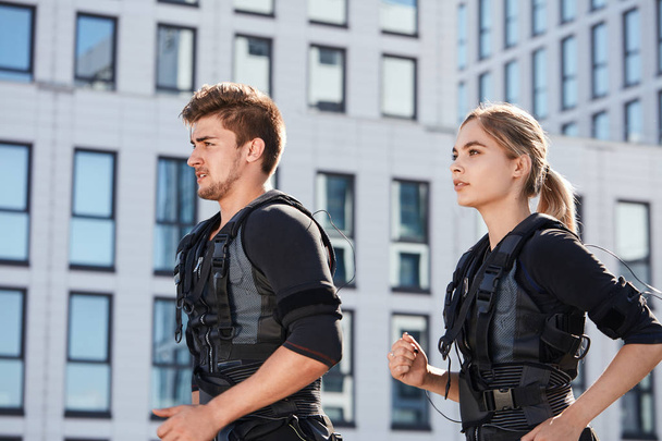 close up side view photo. two young people in EMS suits going jogging - Fotoğraf, Görsel