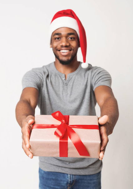 Cheerful black messenger delivering Christmas gift box - Valokuva, kuva