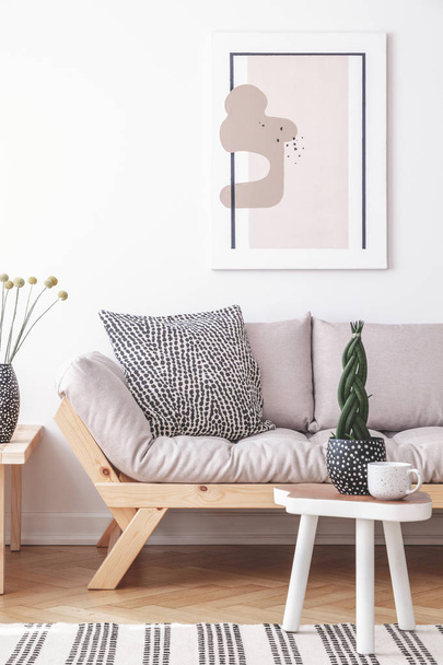 Mock-up painting on a white wall of an artistic living room interior with simple, wooden furniture and patterned decorations - Foto, afbeelding