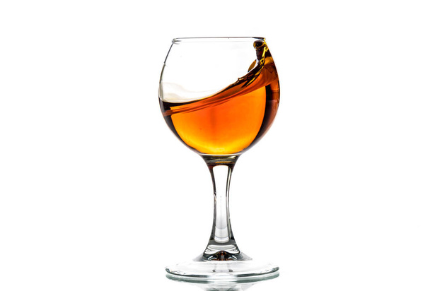 A round glass with brandy and a splash of drink inside - Foto, Imagem