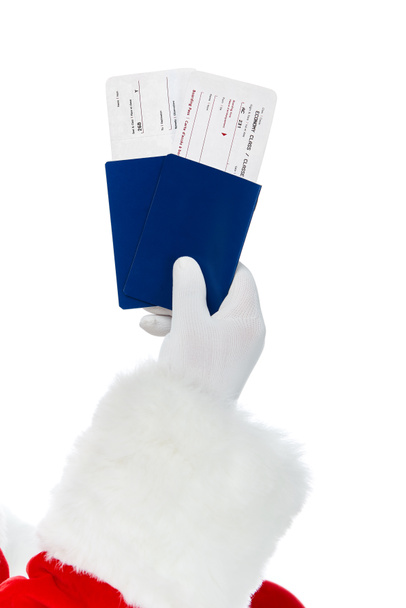 обрезанный вид Санта-Клауса с двумя паспортами и авиабилетами на рождественскую поездку изолированы на белом
 - Фото, изображение