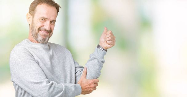 Knappe middenleeftijd senior man die het dragen van een sweater over geïsoleerde achtergrond op zoek trots, lacht doen duimen omhoog gebaar naar de kant - Foto, afbeelding