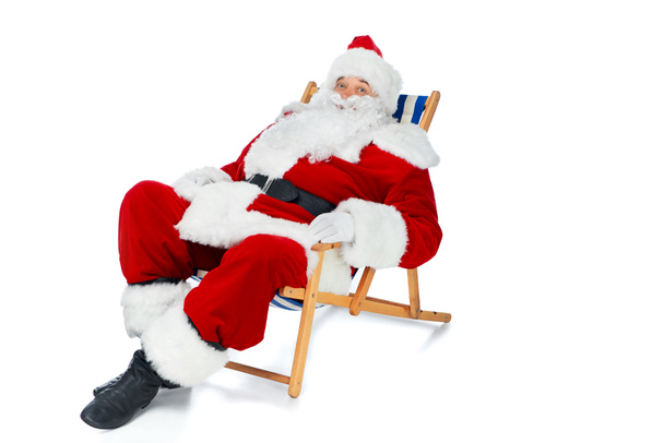 happy santa claus resting on beach chair on white - Foto, afbeelding