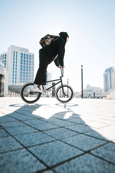 Fiatal férfi bmx kerékpár lovaglás egy napsütéses napon. BMX kerékpár biciklizni a téren. BMX koncepció - Fotó, kép