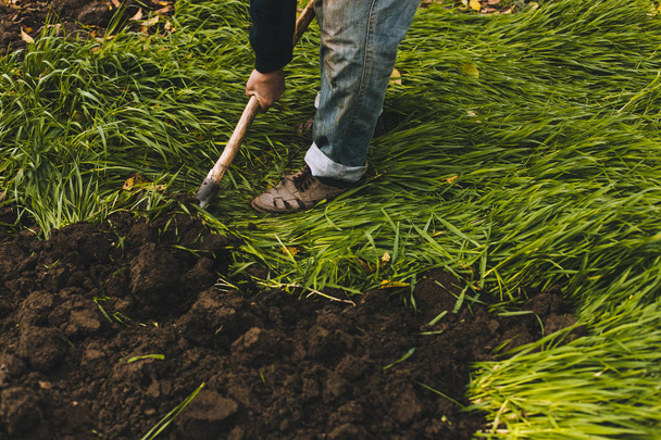 Ο άνθρωπος το σκάψιμο στον κήπο. Σκαλιστικός το χώμα. Ο άνθρωπος σκάβει μια τρύπα για να φυτεψει ένα δέντρο. Ο άνθρωπος χαλαρώνει βρωμιά στο καλλιεργήσιμο έδαφος, κηπουρική, γεωργία και σκληρή εργασία έννοια - Φωτογραφία, εικόνα