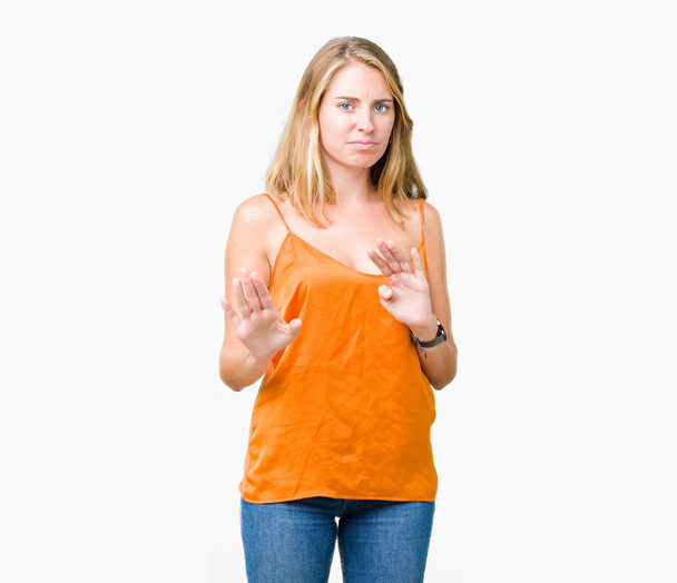 分離の背景にオレンジ色のシャツを着ての美しい若い女性はうんざり表現で、不快と恐ろしいので嫌悪顔をやって嫌悪反応。手で発生します。迷惑な概念. - 写真・画像