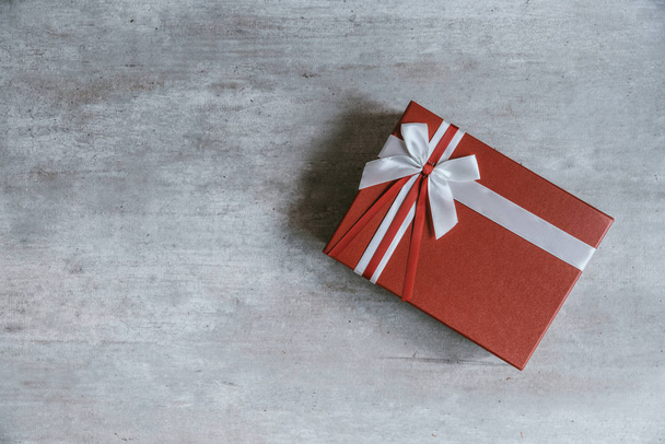 Handgemachtes Weihnachtsgeschenk oder rote Geschenkschachtel in Kraftpapier mit weißer Schleife verpackt. Draufsicht, flache Lage, Kopierraum. Grußkarte. - Foto, Bild