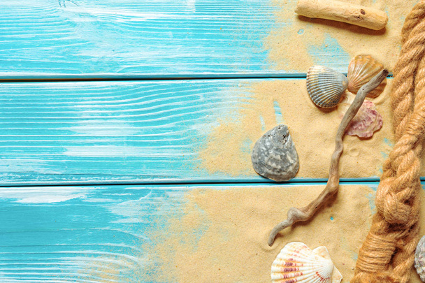 sea rope with sea shells on sea sand on blue wooden background. Top view - Foto, Bild