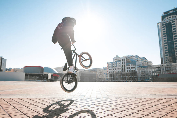 bmx rider macht an einem sonnigen Tag einen Trick auf der Straße. Street-BMX-Kür. - Foto, Bild