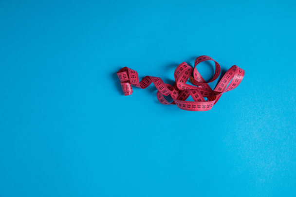 elevated view of pink measuring tape isolated on blue, minimalistic concept  - Photo, Image