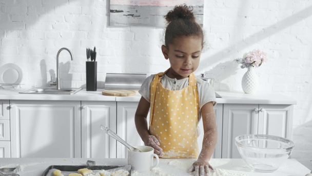 adorable niño afroamericano en delantal tirando harina a la mesa en la cocina
  - Metraje, vídeo