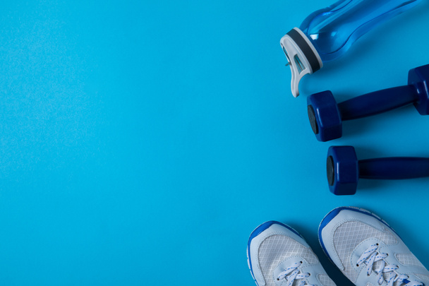 vue surélevée des haltères, baskets et bouteille de sport avec de l'eau isolée sur bleu
  - Photo, image