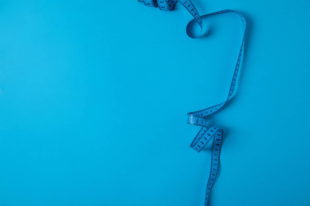 top view of measuring tape isolated on blue, minimalistic concept  - 写真・画像