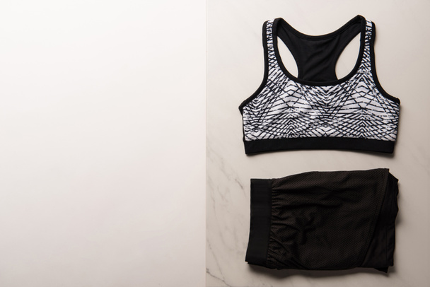 view from above of sports bra with shorts on marble and white, minimalistic concept  - Foto, imagen