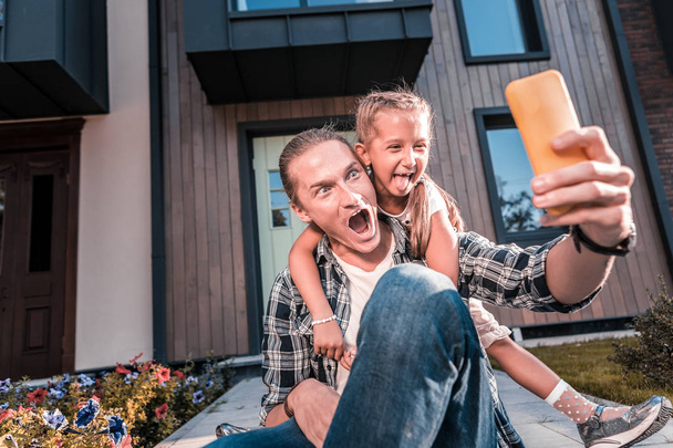 Funny happy father and daughter making funny faces while making selfie - Foto, Bild