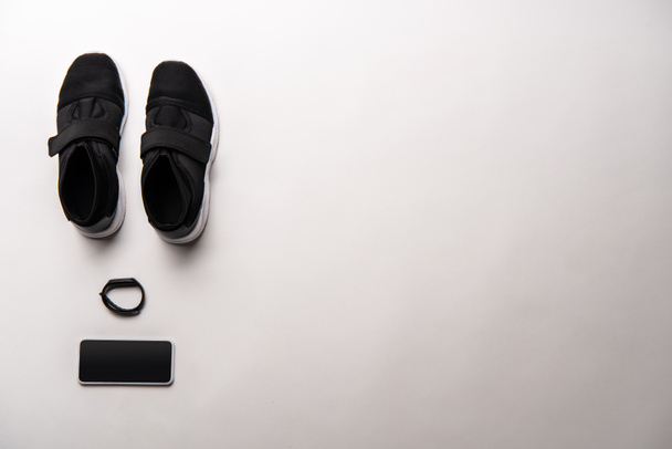 vue de dessus de chaussures de sport noires disposées, d'un traqueur de fitness et d'un smartphone avec écran vierge isolé sur blanc
 - Photo, image