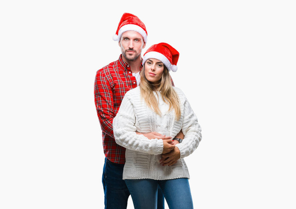 Giovane coppia innamorata indossa cappello di Natale su sfondo isolato con espressione seria sul viso. Semplice e naturale guardando la fotocamera
. - Foto, immagini
