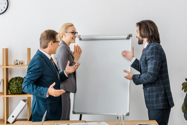 smiling office workers pointing at white board at meeting  - Photo, Image