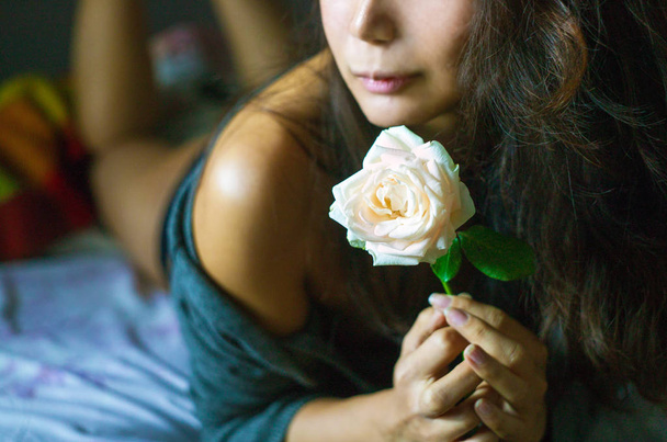 Beautiful asian woman in bed with white rose in the morning. - Photo, image