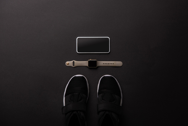 plano con smartphone arreglado, smartwatch y zapatillas aisladas en negro, concepto minimalista
  - Foto, Imagen