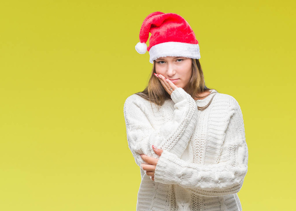 Νεαρή όμορφη γυναίκα Καυκάσιος φορώντας καπέλο Χριστουγέννων πάνω από απομονωμένες υπόβαθρο σκέψης ψάχνει κουρασμένη και τρυπημένο με προβλήματα κατάθλιψης με σταυρωμένα χέρια. - Φωτογραφία, εικόνα