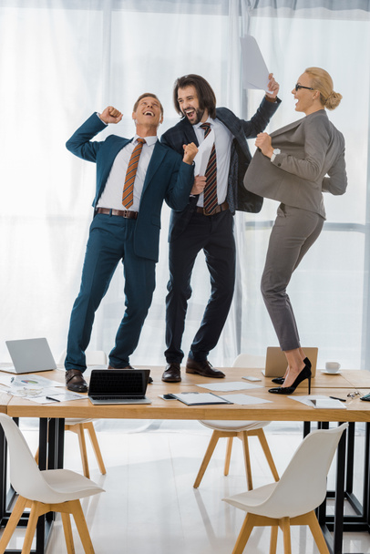 joyeux travailleurs de l'assurance dansant sur la table lors d'une réunion au bureau
 - Photo, image