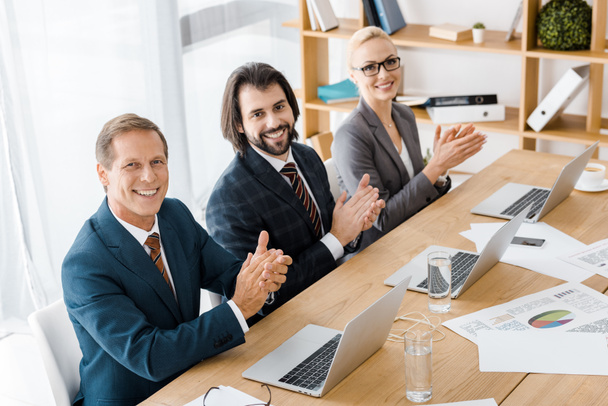 smiling business people clapping hands at meeting in office - Photo, Image