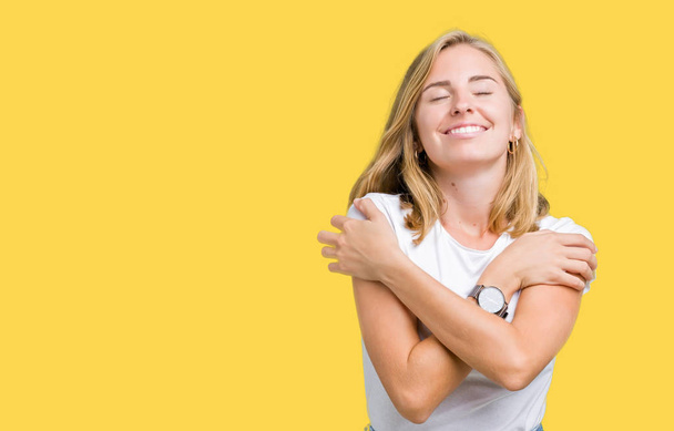 Красива молода жінка в повсякденній білій футболці над ізольованим тлом переслідує себе щасливим і позитивним, посміхаючись впевнено. самодопомоги і самодопомоги
 - Фото, зображення