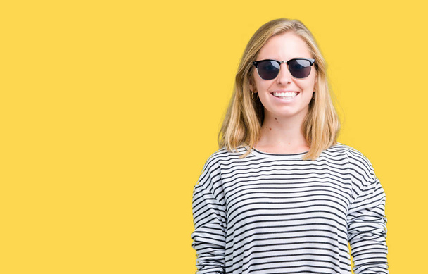 schöne junge Frau mit Sonnenbrille über isoliertem Hintergrund mit einem fröhlichen und kühlen Lächeln im Gesicht. Glück gehabt. - Foto, Bild