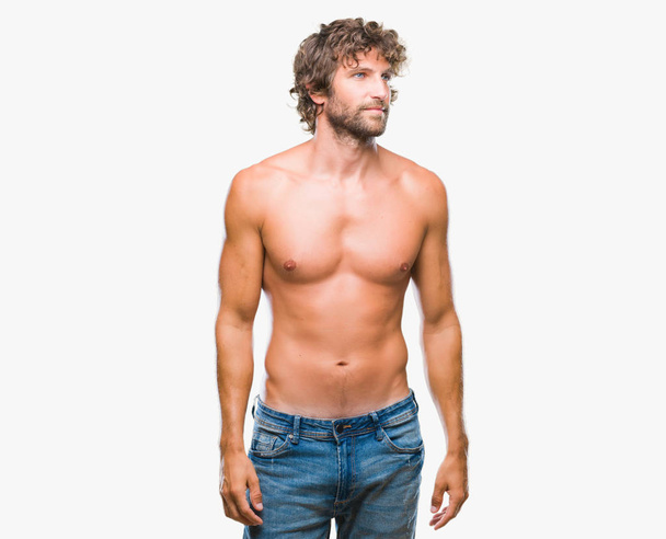 Handsome hispanic model man sexy and shirtless over isolated background looking away to side with smile on face, natural expression. Laughing confident. - Foto, imagen
