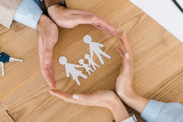 couple making circle with hands on wooden table with paper people inside - Photo, Image
